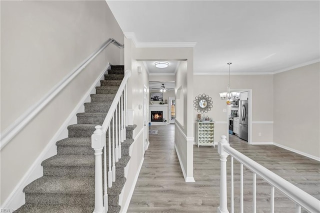 841 Mill Landing Rd, Chesapeake, VA 23322 - staircase with wood finished floors, a warm lit fireplace, ornamental molding, ceiling fan, and baseboards