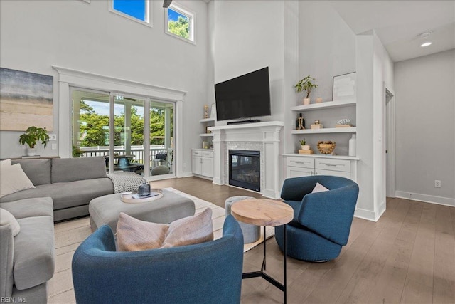 909 Los Colonis Dr, Virginia Beach, VA 23456 - living room featuring a towering ceiling, plenty of natural light, a glass covered fireplace, hardwood / wood-style flooring, and baseboards