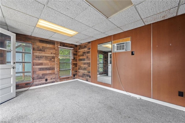 423 Cedar Dr, Hampton, VA 23669 - carpeted empty room featuring wood walls, a wall mounted air conditioner, baseboards, and a drop ceiling