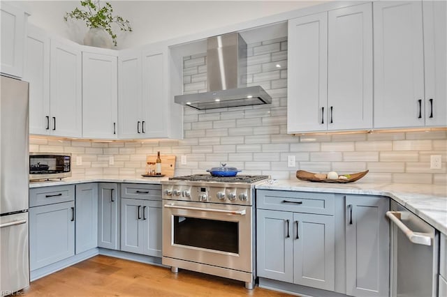 808 High Point Ave, Virginia Beach, VA 23451 - kitchen with wall chimney range hood, appliances with stainless steel finishes, light wood finished floors, light stone countertops, and tasteful backsplash