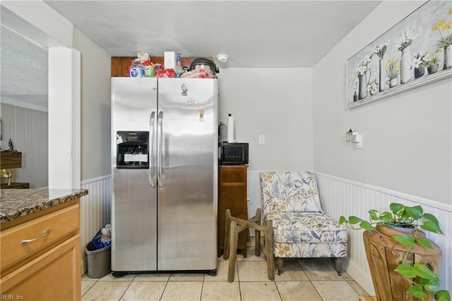5133 E Princess Anne Rd, Norfolk, VA 23502 - kitchen with stainless steel fridge, a wainscoted wall, dark stone counters, light tile patterned floors, and black microwave
