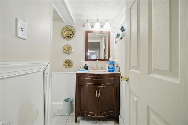 5133 E Princess Anne Rd, Norfolk, VA 23502 - bathroom featuring vanity, a wainscoted wall, a textured ceiling, tile patterned flooring, and a decorative wall