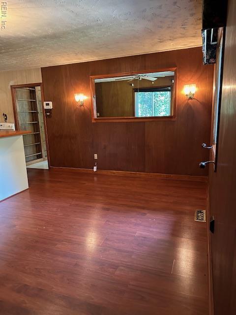 5216 Hemlock Rd, Quinton, VA 23141 - empty room featuring wood finished floors, wood walls, and a textured ceiling