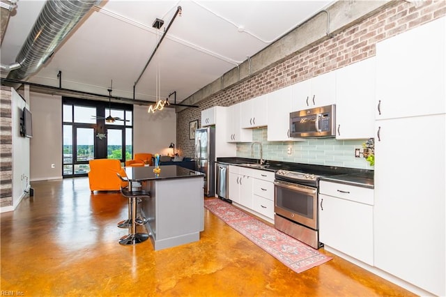 415 Saint Pauls Blvd Unit 702, Norfolk, VA 23510 - kitchen featuring stainless steel appliances, dark countertops, concrete floors, a high ceiling, and brick wall