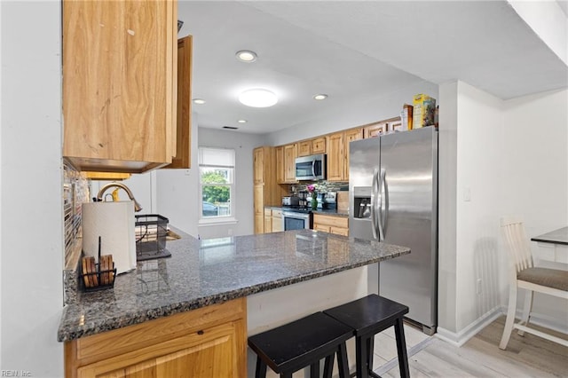 560 Davis St, Virginia Beach, VA 23462 - kitchen featuring appliances with stainless steel finishes, light wood-style flooring, a peninsula, a breakfast bar area, and backsplash