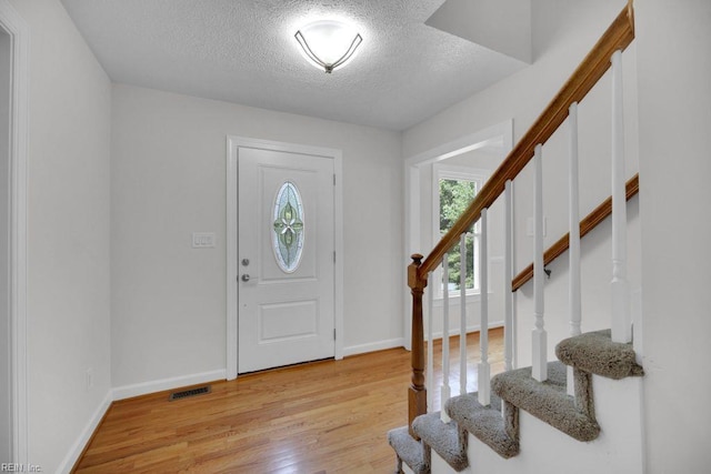 105 Londonderry Ln, Williamsburg, VA 23188 - foyer featuring a textured ceiling, light wood-style flooring, baseboards, and stairs