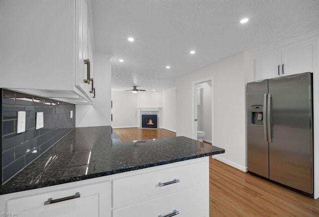 105 Londonderry Ln, Williamsburg, VA 23188 - kitchen featuring stainless steel fridge, white cabinets, recessed lighting, tasteful backsplash, and a warm lit fireplace
