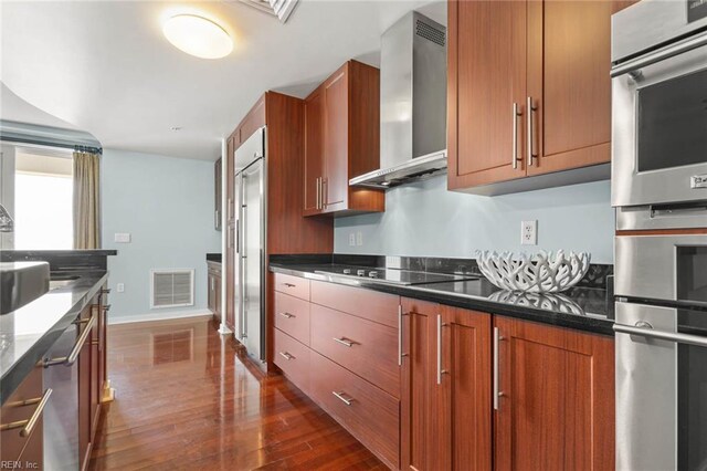 3738 Sandpiper Rd Unit 413, Virginia Beach, VA 23456 - kitchen featuring wall chimney exhaust hood, dark wood-style floors, stainless steel appliances, brown cabinetry, and baseboards