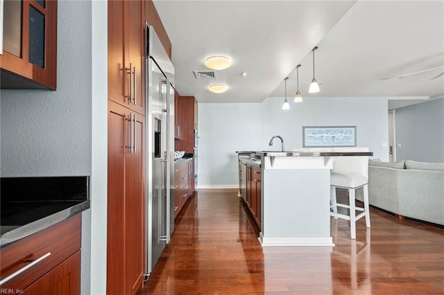 3738 Sandpiper Rd Unit 413, Virginia Beach, VA 23456 - kitchen featuring brown cabinets, a kitchen bar, dark wood-style flooring, open floor plan, and an island with sink