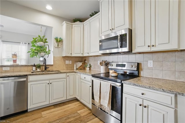 2685 Robert Monette Ln, Virginia Beach, VA 23456 - kitchen with stainless steel appliances, a sink, tasteful backsplash, light stone countertops, and light wood finished floors