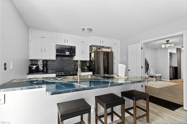 686 Aylesbury Dr, Virginia Beach, VA 23462 - kitchen with appliances with stainless steel finishes, white cabinets, a breakfast bar, tasteful backsplash, and light wood-style floors