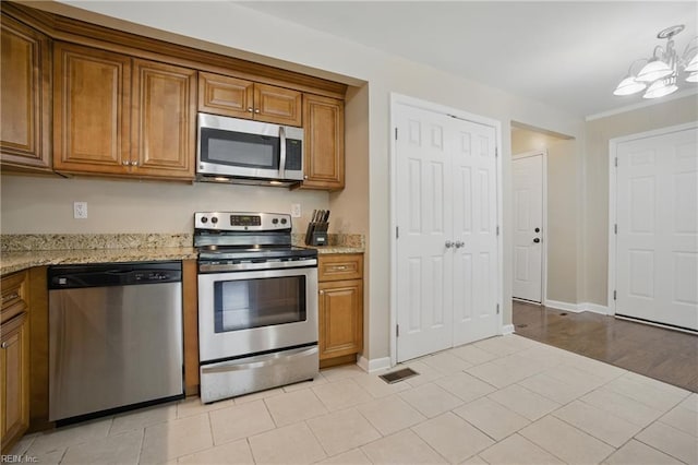 2613 Cedar Rd, Chesapeake, VA 23323 - kitchen featuring appliances with stainless steel finishes, brown cabinetry, light stone counters, and baseboards