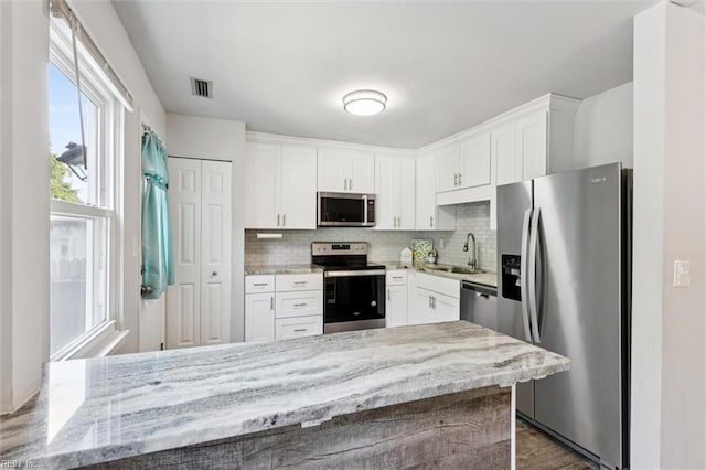3054 Comte Ct, Virginia Beach, VA 23453 - kitchen featuring appliances with stainless steel finishes, a sink, decorative backsplash, white cabinetry, and light stone counters