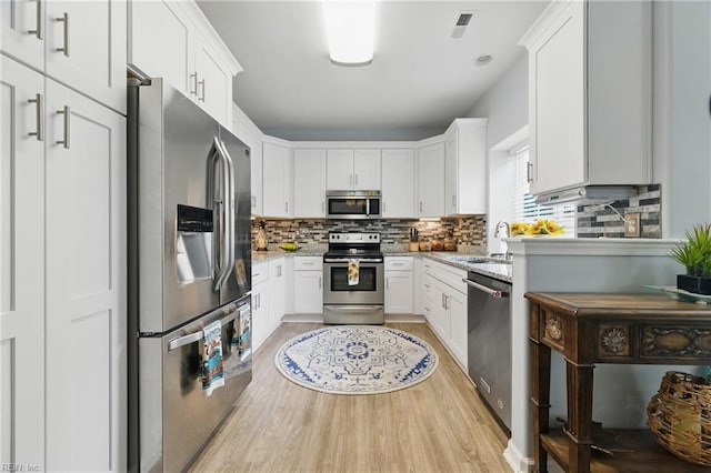 13435 Prince Andrew Trl, Carrollton, VA 23314 - kitchen with appliances with stainless steel finishes, light wood finished floors, decorative backsplash, and light stone countertops