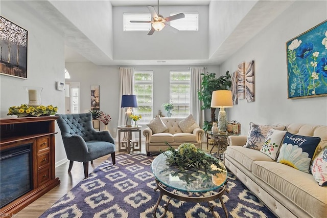 13435 Prince Andrew Trl, Carrollton, VA 23314 - living area featuring a ceiling fan, a towering ceiling, wood finished floors, and a glass covered fireplace