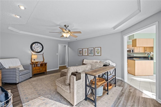 2753 Elson Green Ave, Virginia Beach, VA 23456 - living room featuring ceiling fan, light wood-type flooring, a textured ceiling, a tray ceiling, and baseboards
