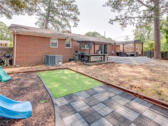 1803 Revere Dr, Hampton, VA 23664 - rear view of house with a pergola, brick siding, central AC, a wooden deck, and a playground