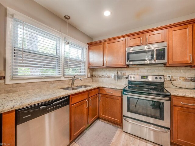 1803 Revere Dr, Hampton, VA 23664 - kitchen featuring stainless steel appliances, a sink, backsplash, brown cabinets, and light stone counters