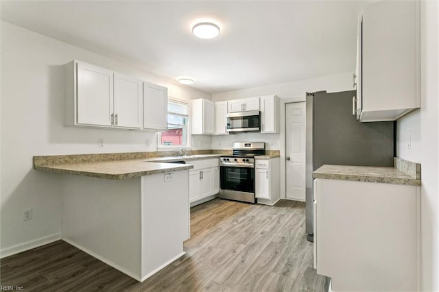 4 Greenwood Dr, Hampton, VA 23666 - kitchen featuring appliances with stainless steel finishes, light wood-type flooring, a peninsula, and white cabinetry