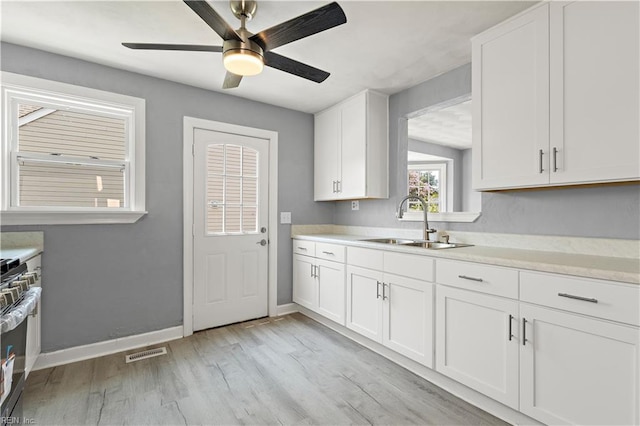 1020 Philpotts Rd, Norfolk, VA 23513 - kitchen with a sink, light countertops, a ceiling fan, white cabinets, and light wood-type flooring