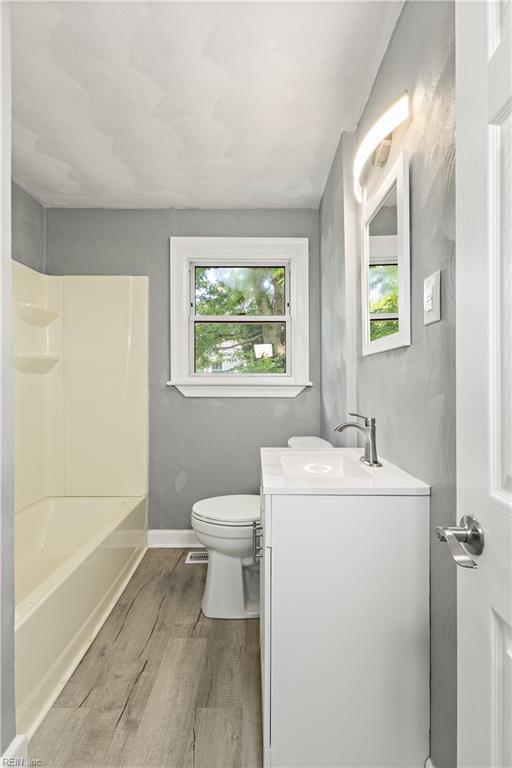1020 Philpotts Rd, Norfolk, VA 23513 - bathroom featuring vanity, wood finished floors, toilet, baseboards, and shower / tub combination
