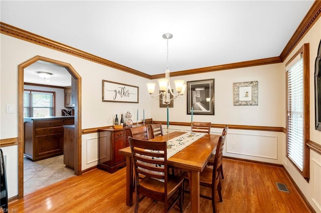 4712 Condor Dr, Chesapeake, VA 23321 - dining space with light wood finished floors, a chandelier, a wainscoted wall, ornamental molding, and a decorative wall