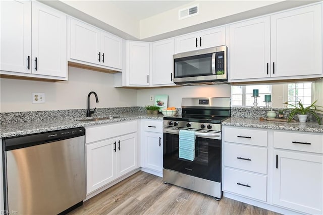 785 Biltmore Dr, Virginia Beach, VA 23454 - kitchen featuring appliances with stainless steel finishes, a sink, white cabinetry, light wood-style flooring, and light stone counters