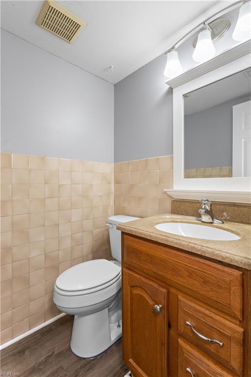 304 Odd Rd, Poquoson, VA 23662 - half bathroom with wood finished floors, vanity, tile walls, toilet, and a wainscoted wall