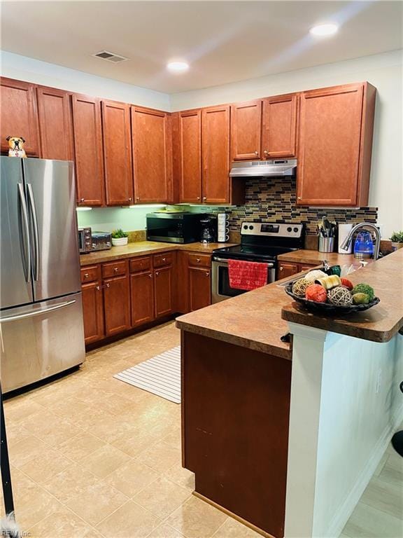 5201 Nuthall Dr Unit 204, Virginia Beach, VA 23455 - kitchen with appliances with stainless steel finishes, under cabinet range hood, a peninsula, backsplash, and brown cabinetry