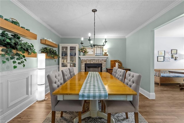 1216 New Born Ct, Chesapeake, VA 23322 - dining space with a chandelier, a textured ceiling, wood finished floors, ornamental molding, and a brick fireplace