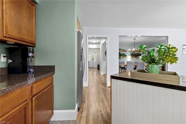 1216 New Born Ct, Chesapeake, VA 23322 - kitchen with light wood-type flooring, stainless steel fridge with ice dispenser, brown cabinetry, baseboards, and a chandelier
