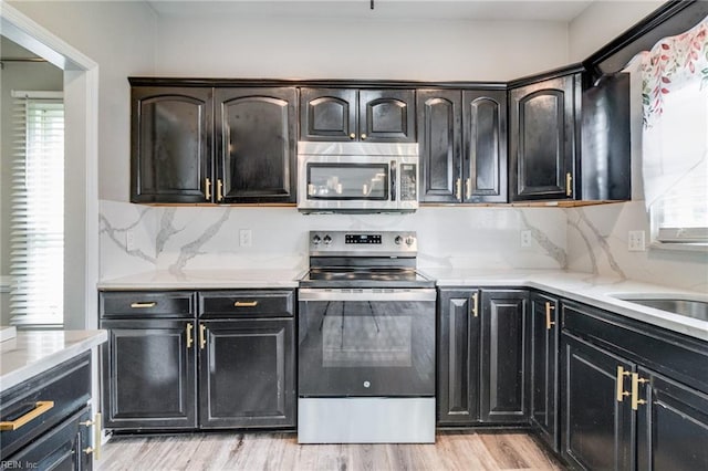 32 Gunter Ct, Hampton, VA 23666 - kitchen with appliances with stainless steel finishes, light wood-type flooring, decorative backsplash, dark cabinets, and light stone countertops