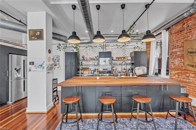 111 W Tazewell St Unit 200, Norfolk, VA 23510 - bar with appliances with stainless steel finishes, dark wood-style floors, brick wall, pendant lighting, and baseboards