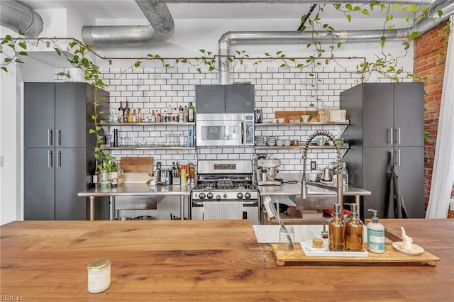 111 W Tazewell St Unit 200, Norfolk, VA 23510 - kitchen with appliances with stainless steel finishes, backsplash, and brick wall
