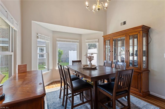 2389 Kerr Dr, Virginia Beach, VA 23454 - dining area featuring wood finished floors, a chandelier, a towering ceiling, and baseboards