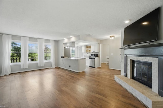1305 Ettington Ln, Virginia Beach, VA 23464 - unfurnished living room with a fireplace, healthy amount of natural light, wood finished floors, a textured ceiling, and baseboards