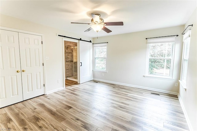 2408 Raynor Ct, Virginia Beach, VA 23456 - unfurnished bedroom with a barn door, light wood-type flooring, baseboards, and a closet