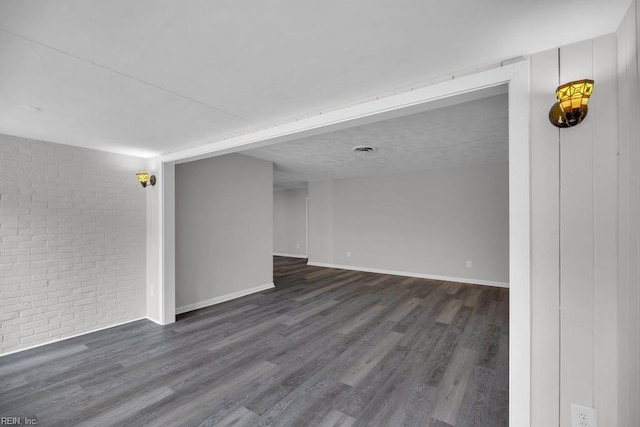 376 Merrimac Trl Unit 113, Williamsburg, VA 23185 - unfurnished room featuring dark wood finished floors, baseboards, and brick wall