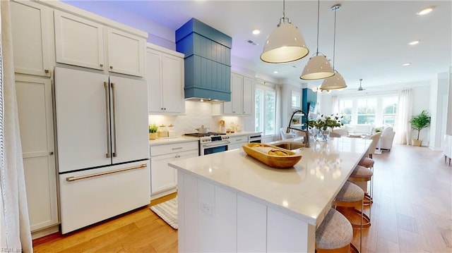 909 Jennings Ln, Chesapeake, VA 23322 - kitchen with white refrigerator, stainless steel stove, a sink, light wood-style floors, and a center island with sink