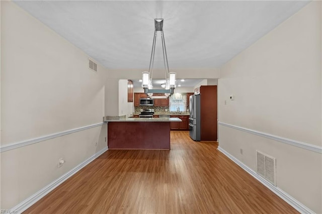 10 Kathy Dr, Poquoson, VA 23662 - kitchen featuring appliances with stainless steel finishes, a peninsula, wood finished floors, backsplash, and light countertops