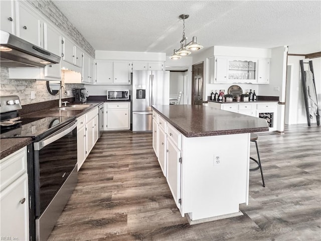 4657 Revere Dr, Virginia Beach, VA 23456 - kitchen with appliances with stainless steel finishes, exhaust hood, dark countertops, a sink, and a center island