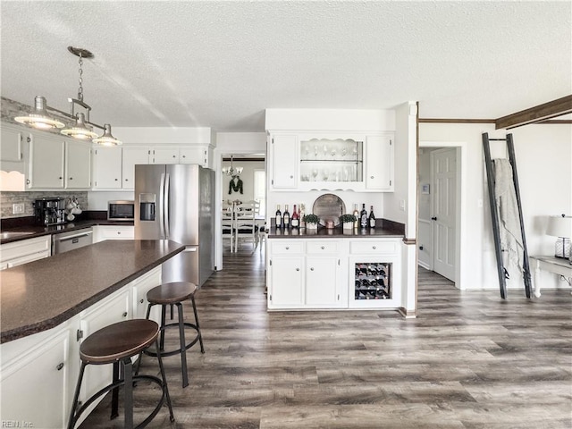 4657 Revere Dr, Virginia Beach, VA 23456 - kitchen featuring stainless steel appliances, dark countertops, a textured ceiling, a breakfast bar area, and dark wood-type flooring