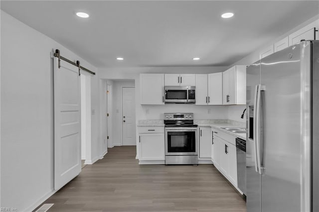 1604 Freeney Ave, Suffolk, VA 23434 - kitchen with stainless steel appliances, a barn door, white cabinets, light countertops, and recessed lighting