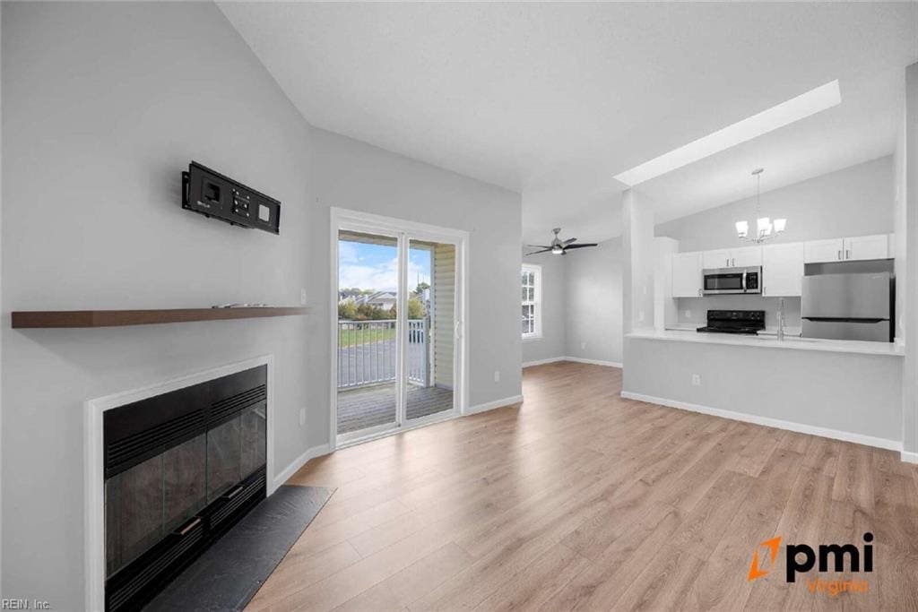 631 Bluff Ct, Virginia Beach, VA 23462 - unfurnished living room with a fireplace with flush hearth, a chandelier, light wood finished floors, vaulted ceiling, and baseboards