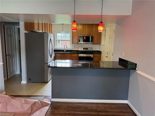 2 Yulee Ct, Hampton, VA 23669 - kitchen with stainless steel appliances, a peninsula, brown cabinets, hanging light fixtures, and a sink
