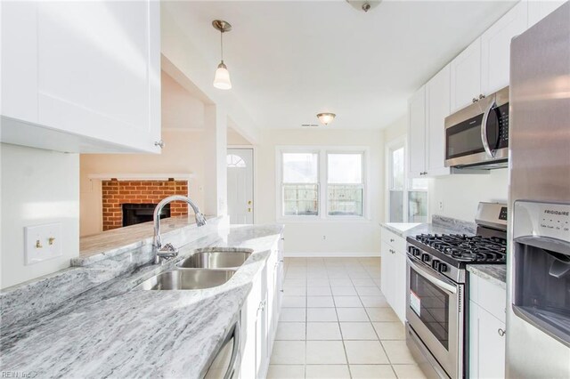 1582 Sword Dancer Dr, Virginia Beach, VA 23454 - kitchen featuring stainless steel appliances, a sink, a brick fireplace, light stone countertops, and white cabinets