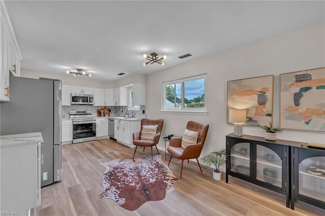 2920 Fetsch Pl, Virginia Beach, VA 23453 - kitchen with appliances with stainless steel finishes, light wood-style floors, white cabinets, and tasteful backsplash
