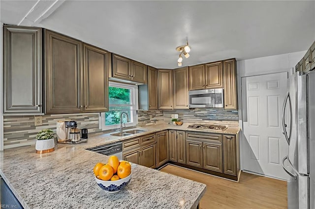 8248 Andrew Ln, Norfolk, VA 23505 - kitchen featuring appliances with stainless steel finishes, a sink, a peninsula, decorative backsplash, and light wood finished floors