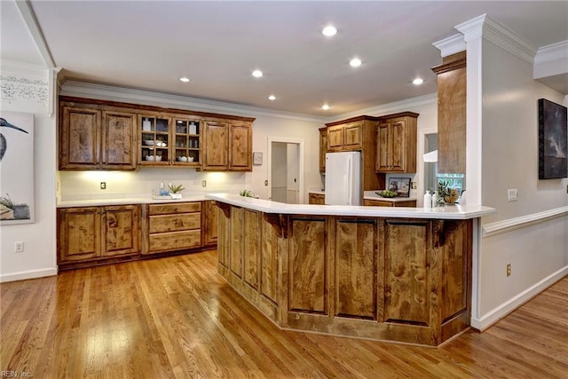 2116 Harpers Ml, Williamsburg, VA 23185 - kitchen featuring freestanding refrigerator, brown cabinets, a peninsula, light wood-type flooring, and glass insert cabinets