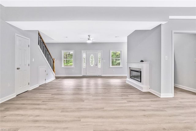 3502 Goodwin Neck Rd, Yorktown, VA 23692 - unfurnished living room with stairs, light wood-style floors, baseboards, a glass covered fireplace, and a ceiling fan